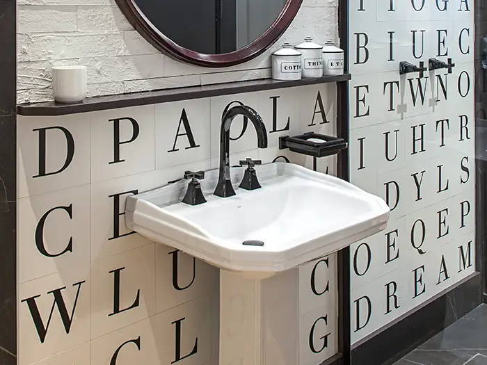 charmantes Waschbecken mit Buchstaben-Motivfliesen im industriellen Look