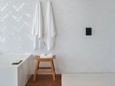 Badezimmerwand mit weißen Fliesen in Fischgrätenmuster von der Rieger – Ihre Bäderschmiede