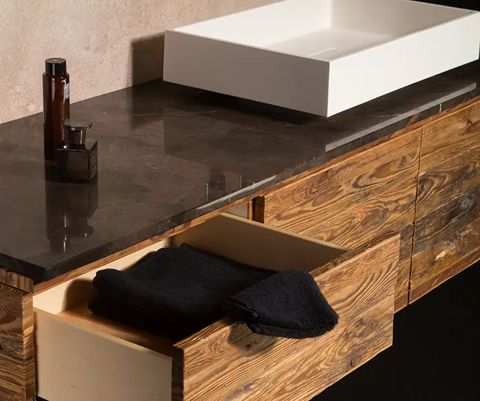 schlichtes Waschbecken mit schwarzer Marmor-Platte und Holz-Unterschrank