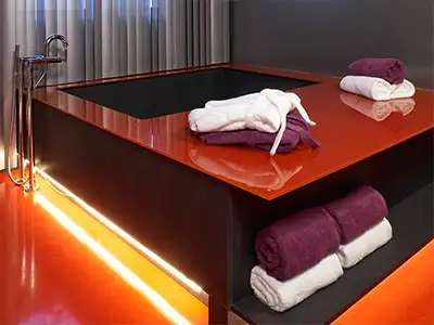 moderne Badewanne mit roter Glas-Ablage und LED-Beleuchtung von der Rieger – Ihre Bäderschmiede