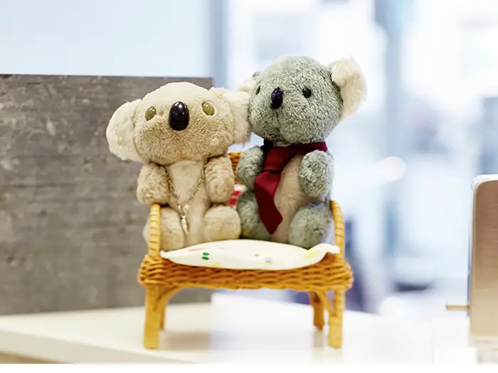 zwei Kuscheltiere auf einem kleinen Rattan-Stuhl von der Rieger – Ihre Bäderschmiede