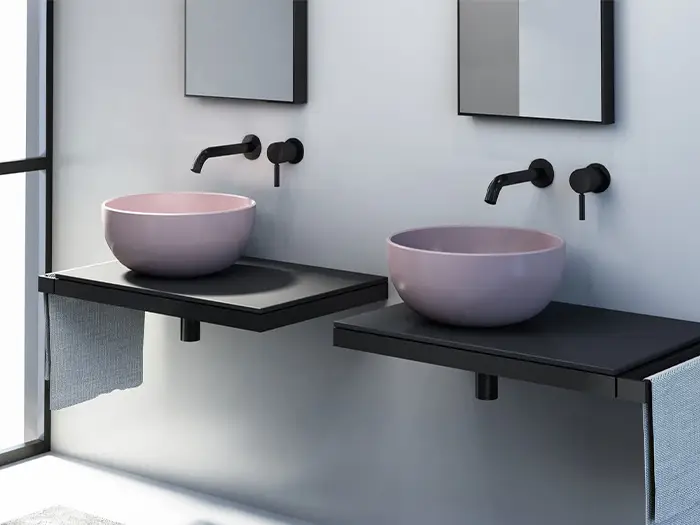 moderne, runde Waschbecken in rosa auf matt-schwarzen Ablagen von der Rieger – Ihre Bäderschmiede