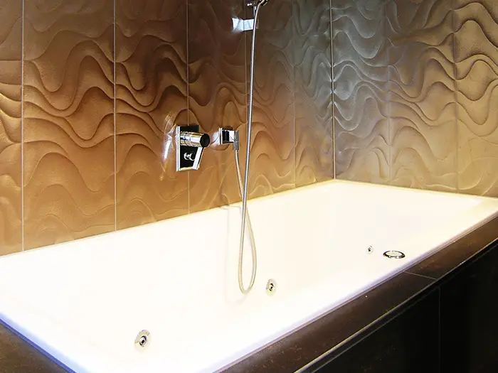 moderne Badewanne mit goldenen Wandpaneelen von der Rieger – Ihre Bäderschmiede
